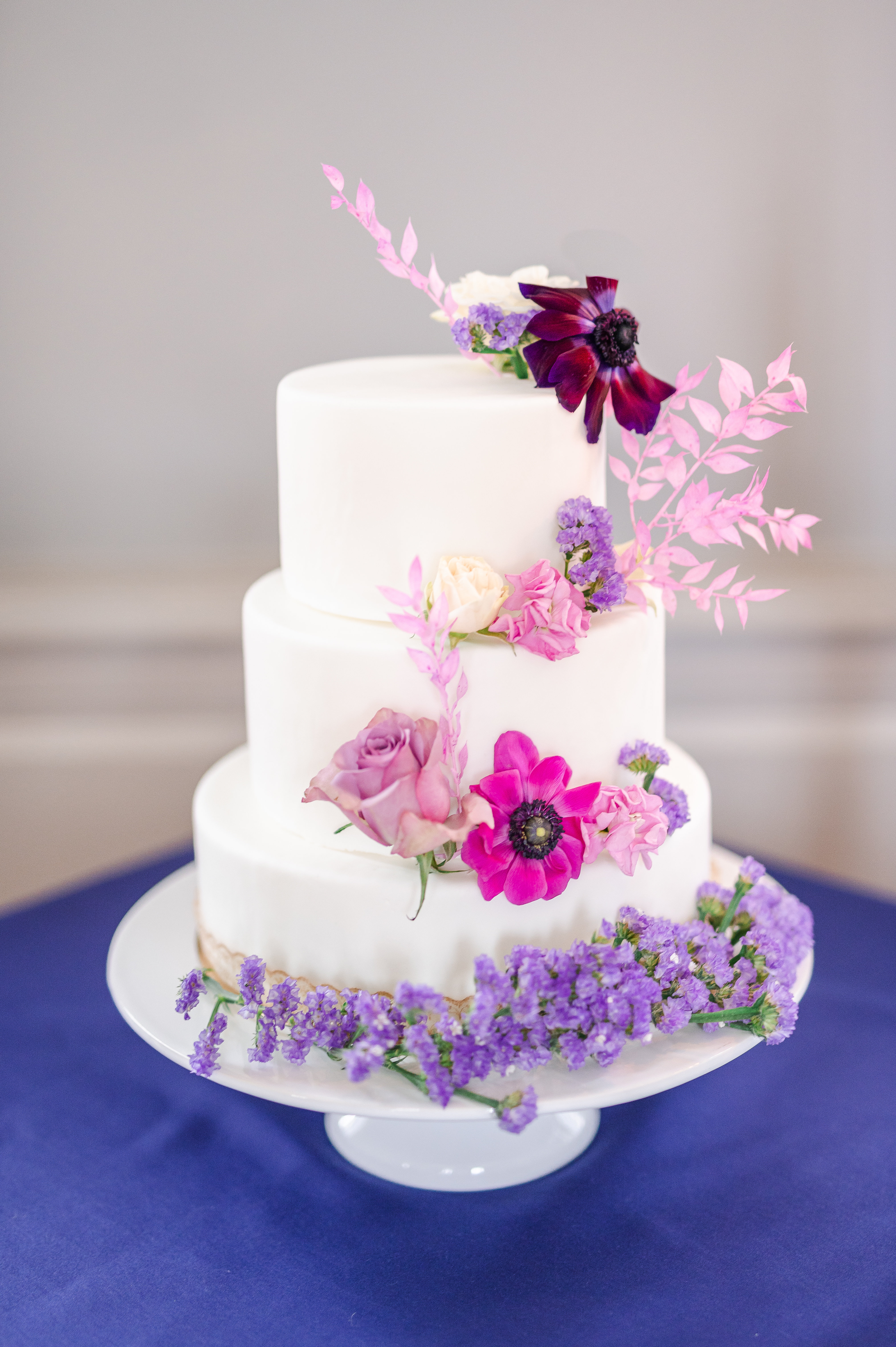 Gâteau de mariage recouvert de pâte à sucre blanche et décoré de fleurs naturelles.